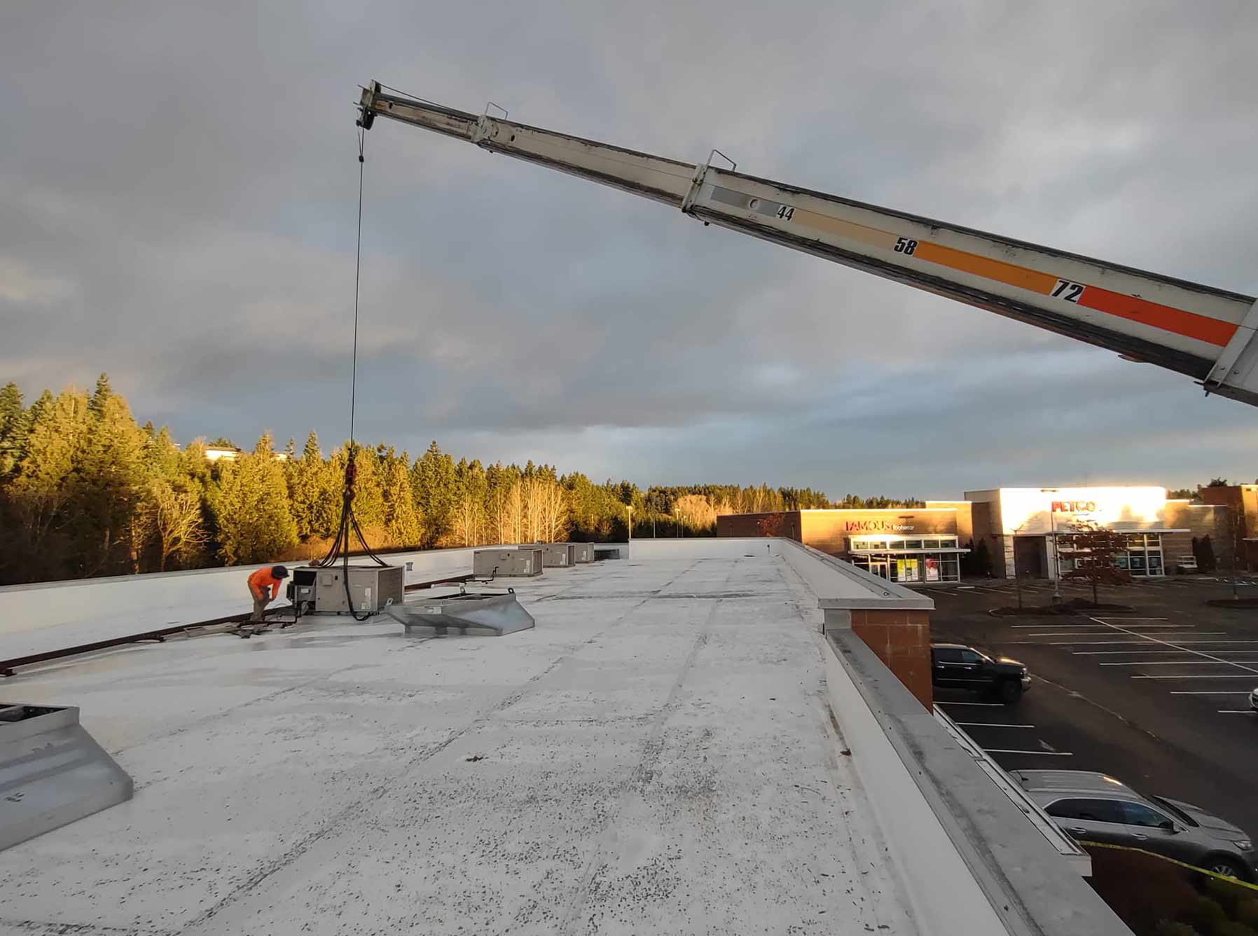 Crane placing rooftop unit on roof